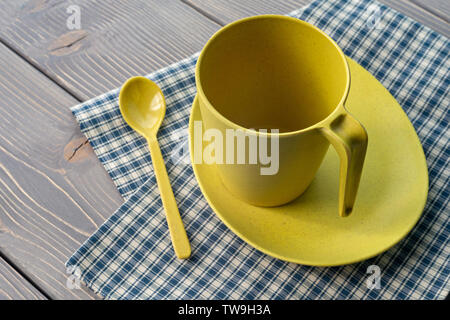 Coupe jaune sur une soucoupe d'une cuillère. Des ustensiles en bambou, avec une serviette à carreaux sur une table en bois. Profondeur de champ. Banque D'Images