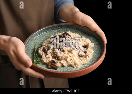 Femme tenant la plaque avec de délicieux risotto et champignons, closeup Banque D'Images
