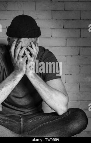 Pauvre homme affamé de pleurer près de brick wall Banque D'Images