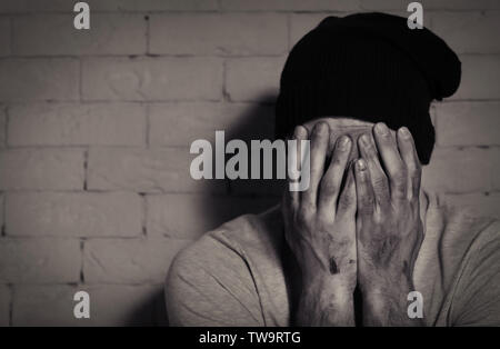 Pauvre homme affamé de pleurer près de brick wall Banque D'Images