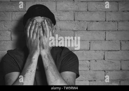 Pauvre homme affamé de pleurer près de brick wall Banque D'Images