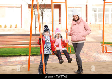 Jeune femme avec des petits enfants sur l'aire de jeux. Adoption de l'enfant Banque D'Images