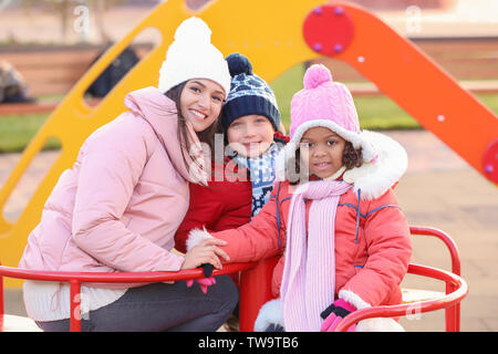 Jeune femme avec des petits enfants sur l'aire de jeux. Adoption de l'enfant Banque D'Images