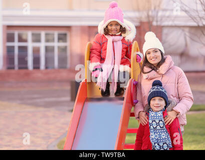 Jeune femme avec des petits enfants sur l'aire de jeux. Adoption de l'enfant Banque D'Images