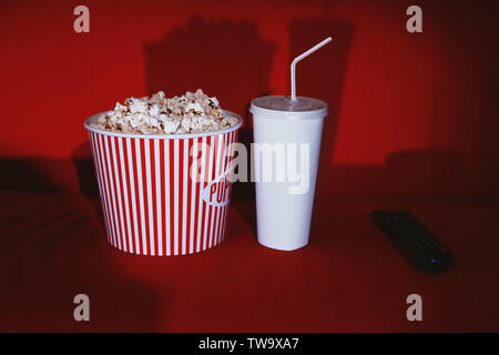 Pop-corn, boissons et de commande à distance sur un canapé confortable. Home cinema Banque D'Images