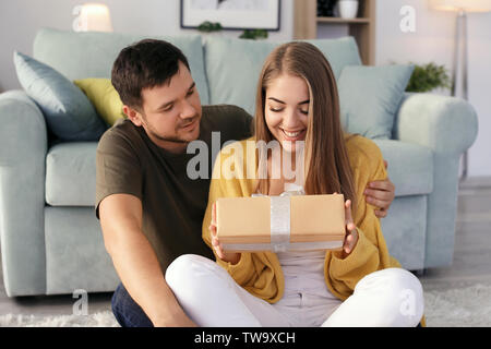 Young woman receiving présente de son cher petit ami à la maison Banque D'Images