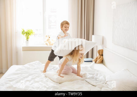 Mignon les enfants s'amusant sur le même lit Banque D'Images