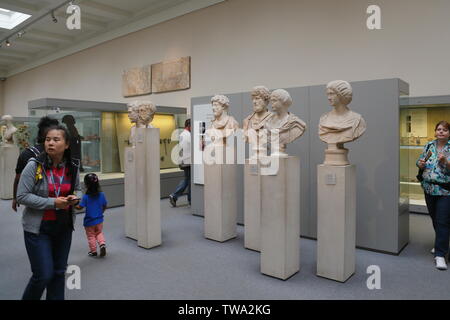 Les visiteurs passent devant la collection de bustes romains de marbre ancien et sculptures exposés au British Museum à Londres, Royaume-Uni. Banque D'Images