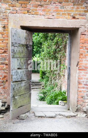 Ouvrir une porte de jardin en bois dans un mur rustique. Banque D'Images