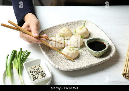 Woman eating tasty baozi quenelles à table Banque D'Images