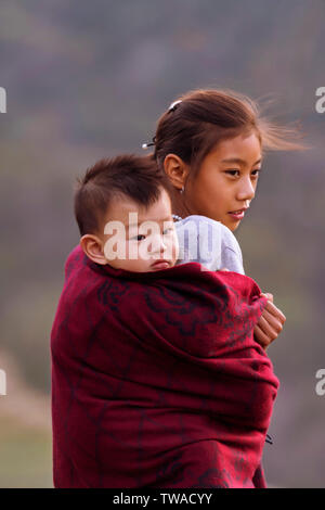 VILLAGE Khonoma, Nagaland, Inde, décembre 2016, jeune fille carryies Naga sœur sur son dos. Banque D'Images