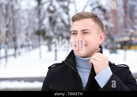 Portrait of happy young man in snowy park sur vacances hiver Banque D'Images