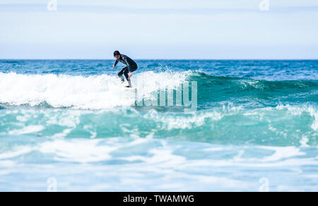 Guy surfeur surf avec surf sur des vagues dans l'océan Atlantique. L'homme en combinaison de surf est actif le surf les vagues de froid de l'océan atlantique en Galice, S Banque D'Images