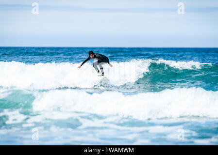 Guy surfeur surf avec surf sur des vagues dans l'océan Atlantique. L'homme en combinaison de surf est actif le surf les vagues de froid de l'océan atlantique en Galice, S Banque D'Images