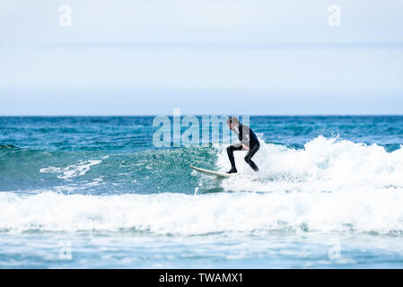 Guy surfeur surf avec surf sur des vagues dans l'océan Atlantique. L'homme en combinaison de surf est actif le surf les vagues de froid de l'océan atlantique en Galice, S Banque D'Images