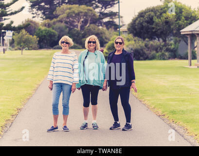 Joli groupe de trois cadres supérieurs retraités mature femmes dans leur 60s walking in sportswear faisant l'exercice quotidien des gens ensemble dans l'amitié féminine Banque D'Images