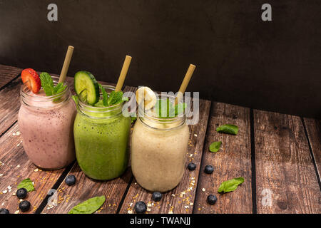 Délicieux produits biologiques banane, fraise et de concombre, de lin et de chia seed smoothies aux fruits tourné sur table en bois contre un arrière-plan en ardoise noire. Pict également Banque D'Images