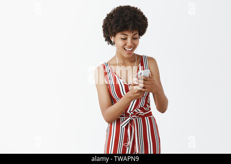 Girl trouvé grande musique qui correspond à son humeur. Heureux et satisfaits dans le quartier branché d'afro-américain de charme salopette rayée, l'écoute au casque de la musique Banque D'Images