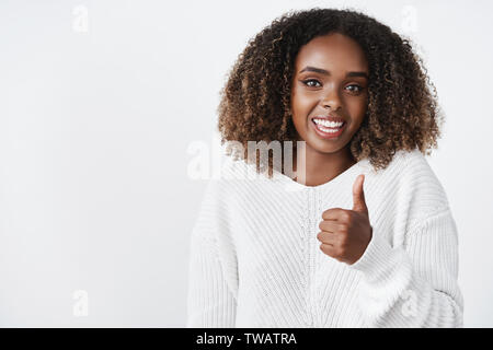 Jusqu'à la taille shot of woman showing thumb up et souriant joyeusement recommander produit, goût awesome outfit de ami comme donnant un avis positif Banque D'Images