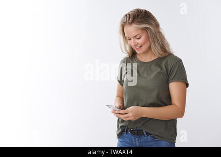 Femme de la consultation des messages en file d'alimentation commande online holding smartphone à sourire amusé et heureux avec à l'écran du téléphone mobile texting Banque D'Images