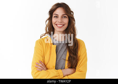 Cheerful young nouvelle femme attrayante employé est prêt à regarder l'appareil photo sous tension optimiste confiant les traverses poitrine auto-assurance smiling but dentelée Banque D'Images