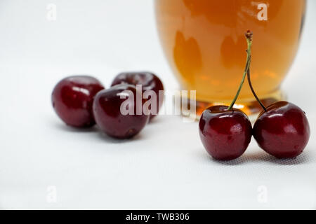 Bouquets de cerises sucrées et une bouteille de jus sains de cerise. Fruits d'été et d'automne. Boisson rafraîchissante à froid de fruits mûrs. Compote de cerises. Banque D'Images