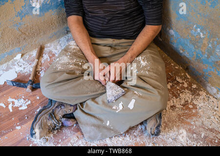 Mason homme ayant un reste après peinture de voiture avec un marteau et un grattoir Banque D'Images