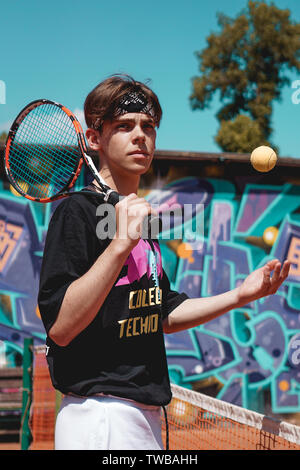 Sport Tennis. L'homme jouant au tennis en plein air. Portrait Of Attractive Young Man In Black T-shirt avec Racket Banque D'Images