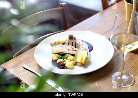 Roulades de poulet farcies au gorgonzola, servi aux poireaux sautés au beurre, boulettes, petits pois et sauce au vin. Banque D'Images