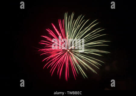 La moitié soit rouge ou rose et l'autre moitié d'artifice blanc explose dans les nuits sombres sky Banque D'Images