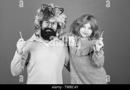 Barbu homme père et fille porter perruque colorée alors que manger des bonbons sucette. Chose père aimant faire pour les enfants. Relations sérieuses in hommage à papa. Des moyens simples facilement être amusant. parent ludique Fou comment est votre père. Banque D'Images