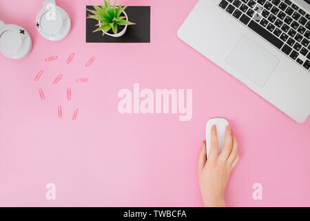 Flatlay stylisée avec women's bureau. Espace de travail avec ordinateur portable, souris d'ordinateur dans la main de femme, succulentes et écouteurs. Copier l'espace. Banque D'Images