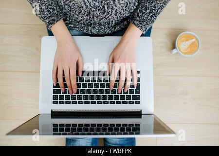 Aperçu d'un freelancer femme place de travail. Les mains des femmes qui tape sur le clavier, une tasse de délicieux café à côté. Banque D'Images