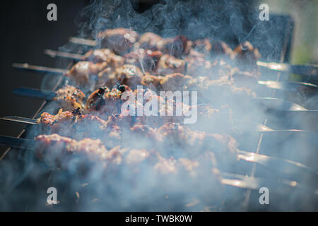 Shish kebab la cuisson en plein air en été. brochettes barbecue sur le grill frit dans la fumée provenant de la combustion. Banque D'Images