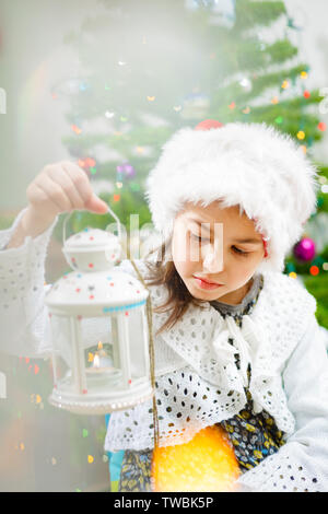 Belle fille dans un chapeau de Noël avec un chandelier dans ses mains, fourrure-arbre Banque D'Images