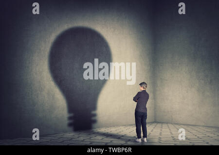 Longueur complète young businesswoman holding hands folded casting une ampoule forme ombre sur le mur. L'ambition et l'idée d'entreprise concept. Motivation et Banque D'Images