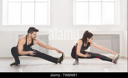 Couple sportif stretching jambes avant la formation en studio, panorama, copy space Banque D'Images