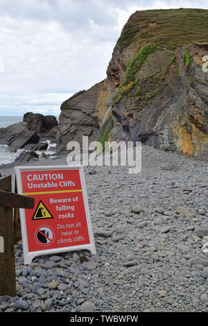 Panneau d'avertissement en vertu de la base de la falaise sur la plage en ce qui concerne le danger d'instabilité de falaise et les chutes de pierres Banque D'Images