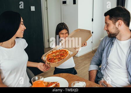 Pizza en famille pour le déjeuner. Petite fille s'amuser avec sa famille Banque D'Images