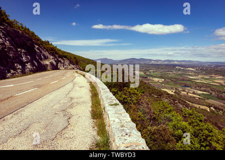 Une route coupe un chemin tel qu'il s'accroche à flanc de montagne dans le sud de la France, à proximité des Gorges de la Nesque. Banque D'Images