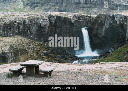 Plate-forme d'observation touristique avec table en bois et marbre. Voir de belle cascade dans les montagnes. Le sud-est de l'Islande, l'Europe. Traitement de l'art ph Banque D'Images