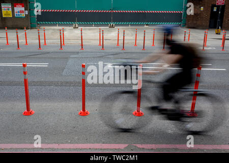 Des vitesses d'un cycliste voie de circulation passé neuf Elms, bollards dans le sud de Londres, le 15 juin 2019, à Londres, en Angleterre. Banque D'Images