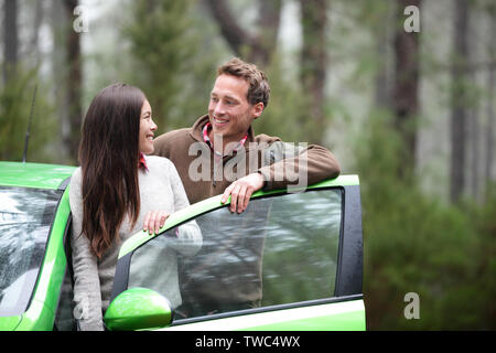 Location Personnes - happy couple driving on road trip en vert nouvelle voiture de location dans une nature magnifique forêt. Couple multiracial romantique sur la route des vacances. Asian Woman, man. Banque D'Images