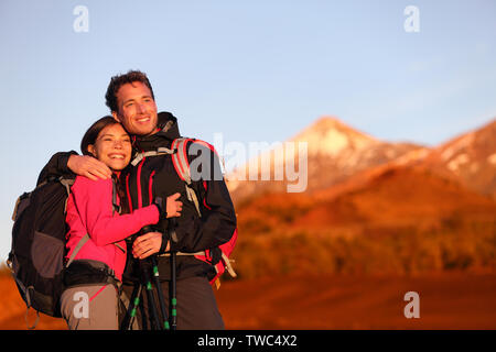 Couple heureux randonnées bénéficiant à la vue à embrasser dans l'amour. Hiker homme et femme portant des sacs à dos pendant le coucher du soleil en randonnée sur le volcan la montagne Teide, Tenerife, Canaries, Espagne. Banque D'Images