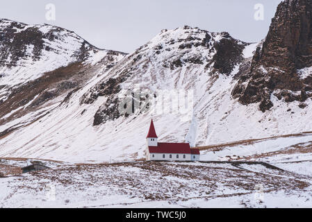 Petite église située au sommet d'une colline, offrant une vue pittoresque sur l'océan et le village de Vik. Banque D'Images