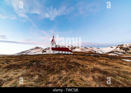 Petite église située au sommet d'une colline, offrant une vue pittoresque sur l'océan et le village de Vik. Banque D'Images