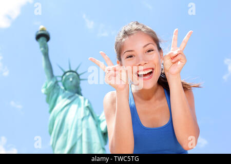 À touristiques Statue de la liberté, New York, USA making funny face à la victoire de l'expression des signes de main excité et heureux. Concept du tourisme et des voyages d'une joyeuse mixed race woman asiatiques. Banque D'Images