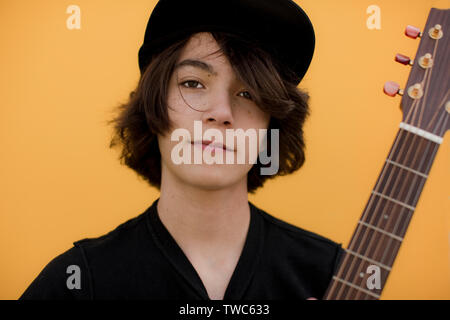 Portrait d'un jeune garçon portant un chapeau et posant avec sa guitare. Banque D'Images