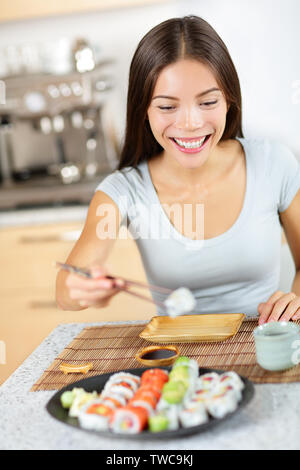 Young pretty asian young asian woman en modèle de vie sain sushi de plaque - à propos de manger des aliments en souriant joyeusement. Assis à table dans la cuisine Banque D'Images