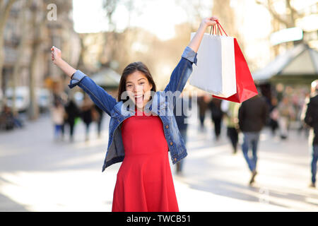 Shopping femme heureuse sur la rue de La Rambla de Barcelone. Shopper girl holding shopping bags excité jusqu'à l'extérieur sur walking street. Mixed Race Woman modèle féminin asiatique cheerful en Espagne. Banque D'Images